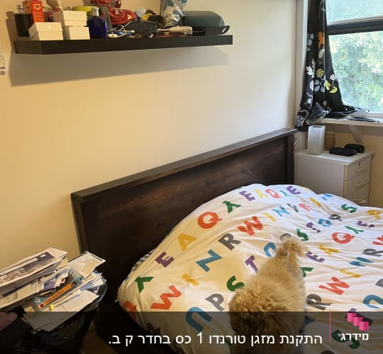 מזגן מותקן על קיר מעל מיטה בחדר שינה